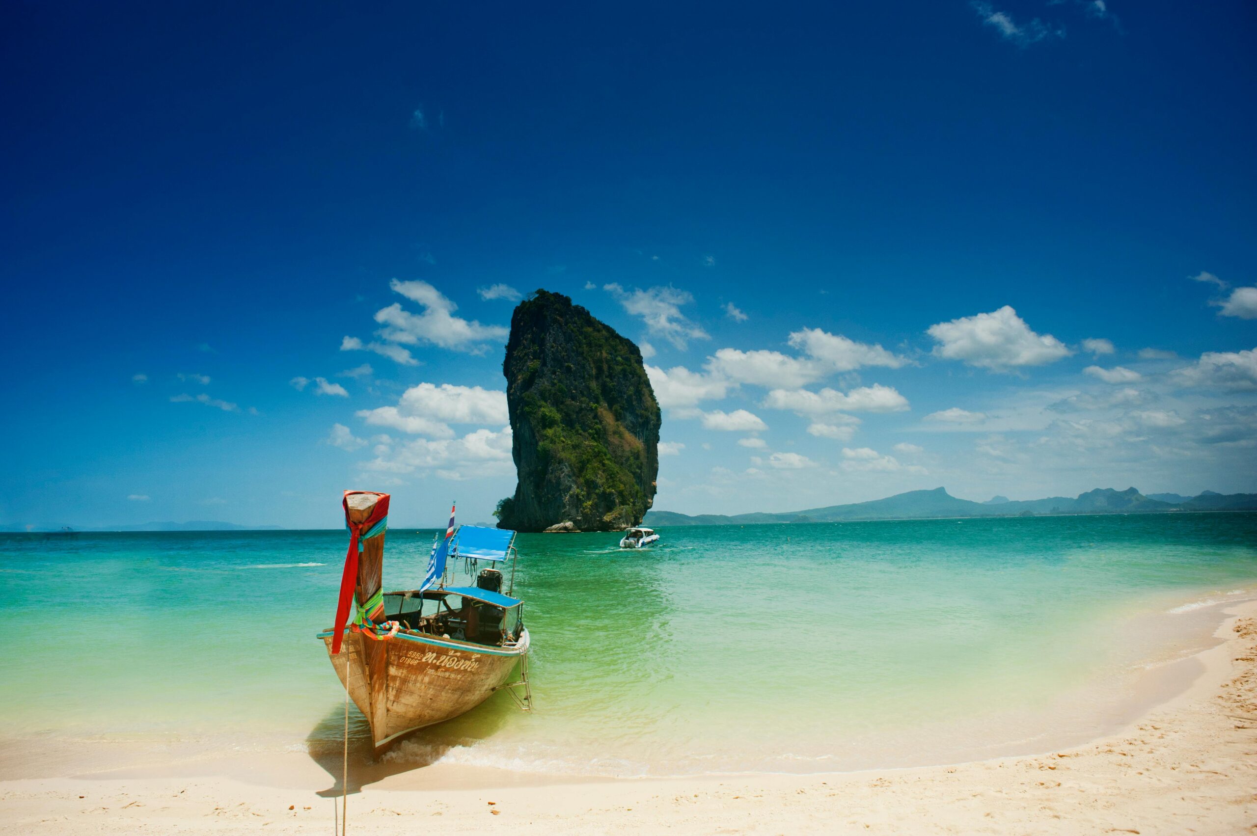 Capture the serene beauty of a Thailand beach with turquoise waters and iconic rock formations.