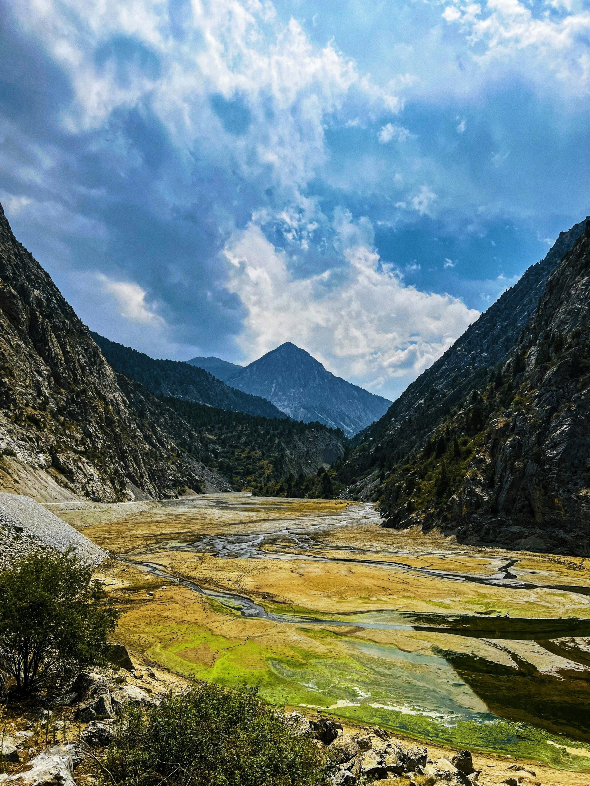 Scenic mountain landscape in Kyzyl-Kiya, Kyrgyzstan with vibrant colors and dramatic clouds.