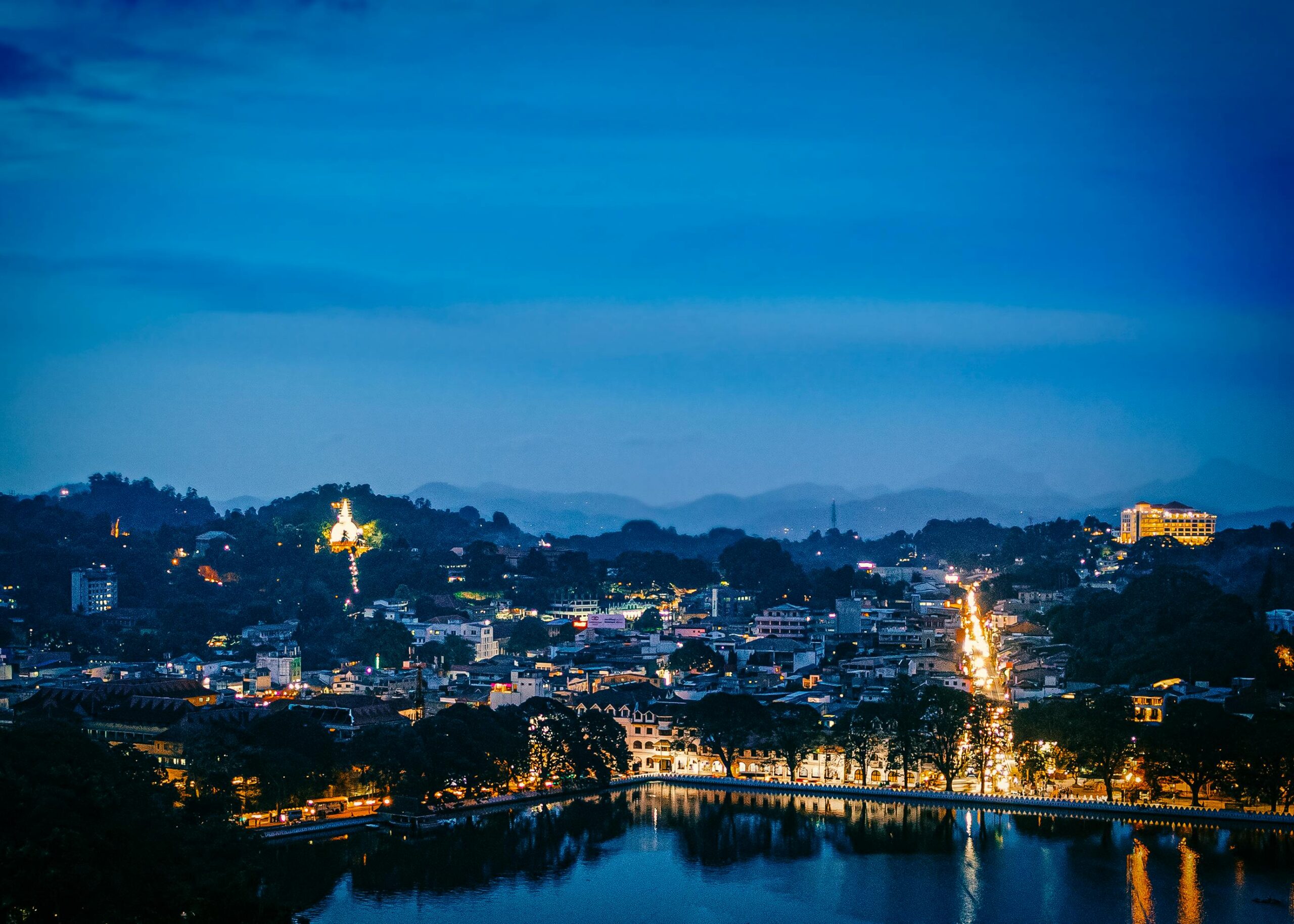 A beautiful aerial view of Kandy, Sri Lanka, at dusk with city lights reflecting on the lake.