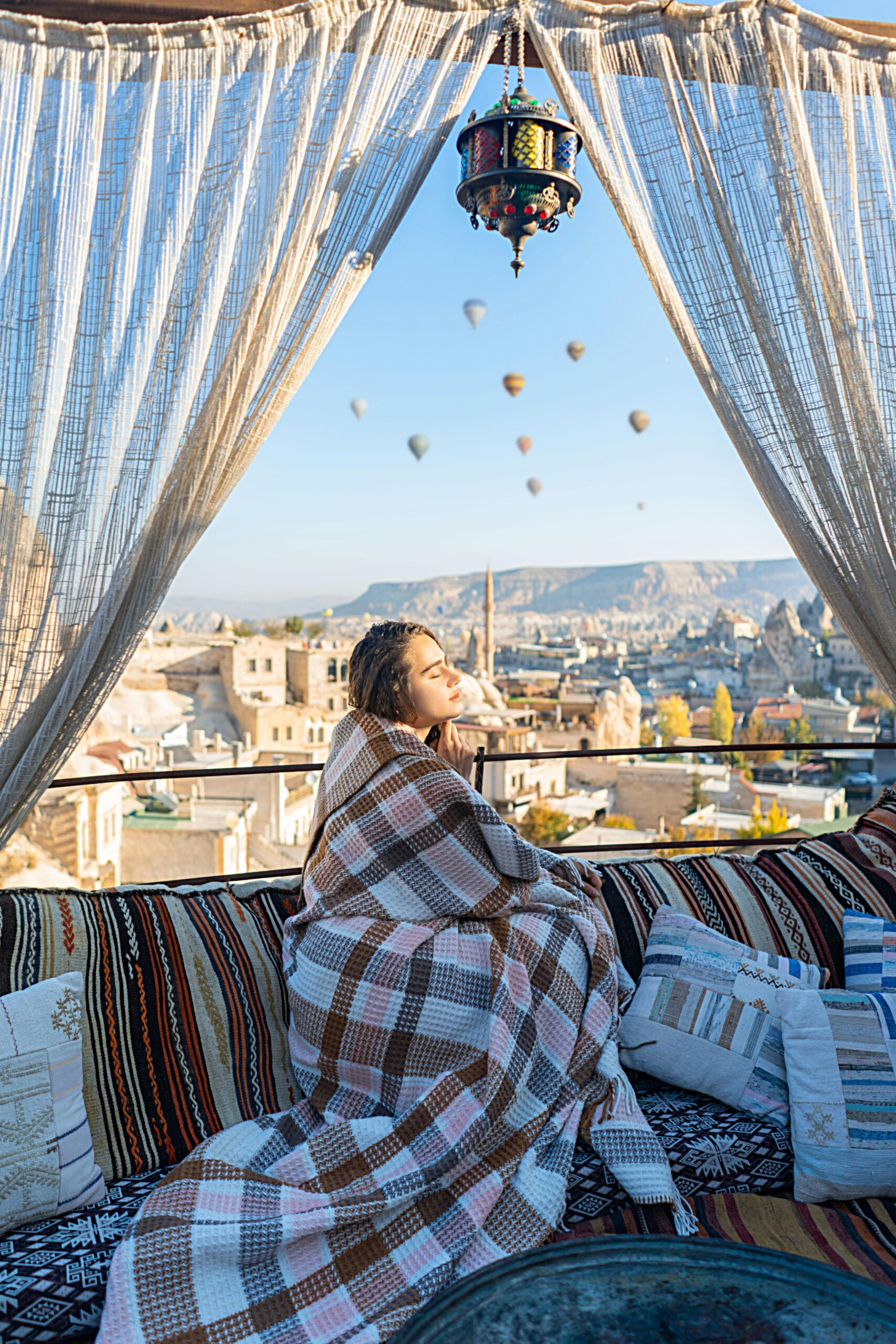 Young woman enjoys scenic view from a Turkish terrace with balloons in the sky.