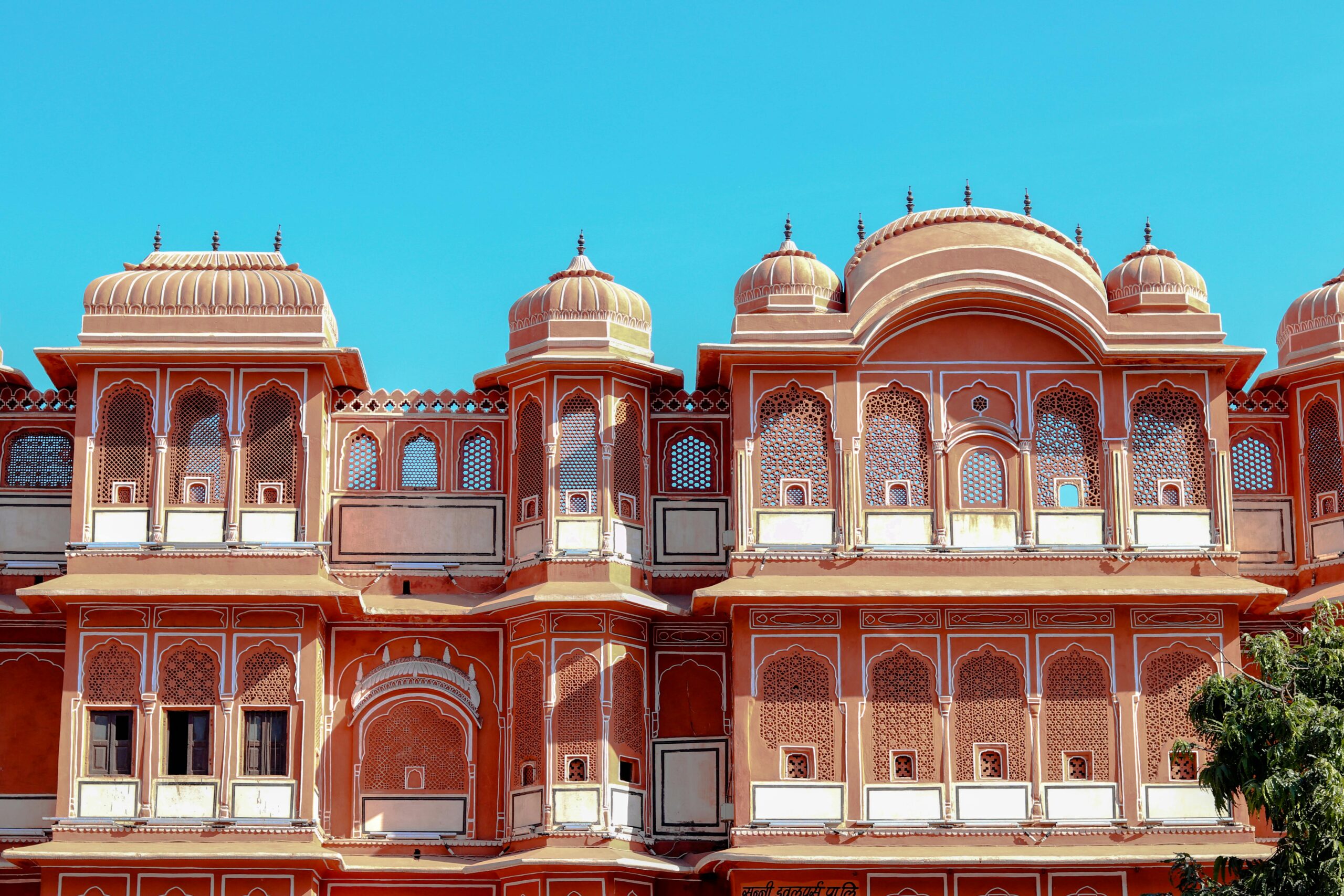 Intricate architectural details of a historic Indian palace facade under a clear blue sky.
